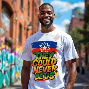 May include: A white t-shirt with a colorful graphic design. The design includes a blue, red, and green brushstroke with a white star and the text "THEY COULD NEVER BE US" in green, yellow, and orange. The person is smiling.