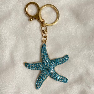 May include: A gold-tone keychain with a blue jeweled starfish charm.
