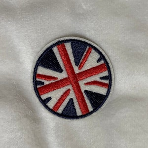 May include: A round, embroidered patch with a red, white, and blue Union Jack design. The patch is perfect for adding a touch of British flair to clothing, bags, or other accessories.
