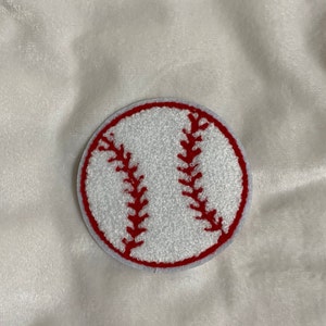 May include: White felt baseball patch with red stitching. The patch is round and has a diameter of approximately 2.5 inches.