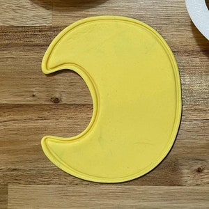 May include: Three white plastic crescent moon cookie cutters. One cutter is a solid shape, one is an outline, and one is a solid shape with a smaller crescent moon cutout inside. The outline cutter has the text "Crescent Moon | 8EF2" printed on it.