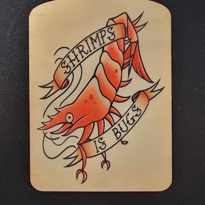 May include: A wooden cutting board with a hand-painted illustration of a shrimp with the text "Shrimps is Bugs" on a banner.