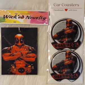 May include: Two round car coasters featuring a red and black Deadpool character with the text "DEADPOOL" printed on each coaster. The coasters are packaged with a black and red car air freshener featuring a Deadpool character with the text "Wick'ed Novelty" on the packaging.