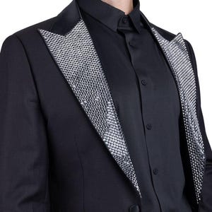 May include: Black tuxedo jacket with a satin lapel and a silver sequin design. The jacket is paired with a black button-down shirt. The formal wear ensemble is suitable for special occasions.