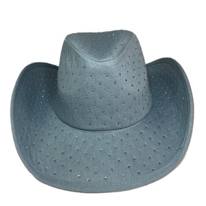 May include: A light blue cowboy hat with a wide brim and a rounded crown. The hat is covered in small, sparkling rhinestones. The hat is made of a soft, denim-like material.