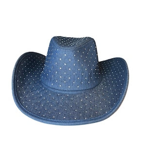 May include: A denim cowboy hat with a wide brim and a crown. The hat is a medium blue color and is covered in small, silver-colored rhinestones. The hat is a classic Western style.