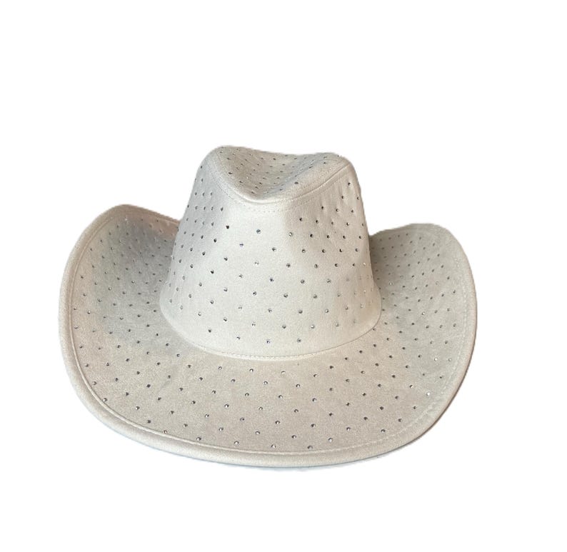 May include: A white cowboy hat with a wide brim and a rounded crown. The hat is adorned with small, evenly spaced rhinestones. The hat is made of a soft, suede-like material.