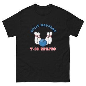 Può includere: T-shirt nero con un design a tema bowling. La grafica include una palla da bowling blu, birilli bianchi e la scritta "SPLIT HAPPENS" in blu sopra i birilli. Sotto, la scritta "7-10 SPLITS" è in rosso.