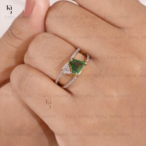 Unique green gemstone statement ring in yellow gold with an asymmetric triangle tourmaline and diamond accents, displayed elegantly on a neutral textured box.