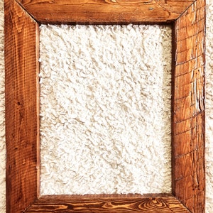 May include: A rustic wooden picture frame with a natural wood finish. The frame has a simple design with a rectangular shape and a slightly distressed look.