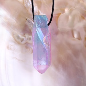 May include: A iridescent pink and blue crystal pendant on a black cord necklace. The pendant is a long, pointed shape.