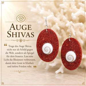 Peut inclure: Une paire de boucles d'oreilles ovales avec une surface rouge texturée et un coquillage en spirale blanc au centre. Les boucles d'oreilles sont suspendues à des crochets argentés. L'image contient le texte AUGE SHIVAS et une citation en allemand.