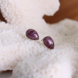 Op de afbeelding: Een paar druppelvormige oorbellen met paarse en roze edelsteenaccenten.