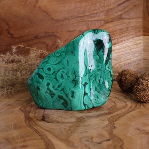 Può includere: Un grande ciottolo di malachite verde con un motivo a spirale e marmo. La pietra è liscia e lucidata, con una finitura lucida.