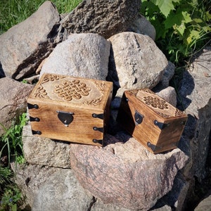 Könnte beinhalten: Zwei Holzkisten mit aufwendig geschnitzten Designs und Metallakzenten. Die Kisten sind geschlossen und haben eine dunkelbraune Oberfläche.