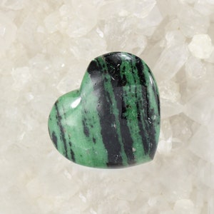 Könnte beinhalten: Ein herzförmiger grüner und schwarzer Edelstein mit einem gestreiften Muster.