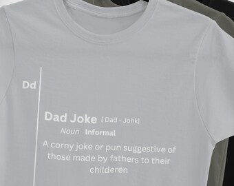 May include: A light gray t-shirt with a white graphic print that defines a "Dad Joke" as a corny joke or pun suggestive of those made by fathers to their children.