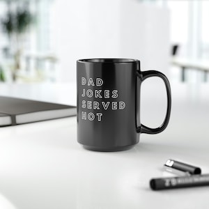 May include: Black coffee mug with white text that reads "DAD JOKES SERVED HOT".