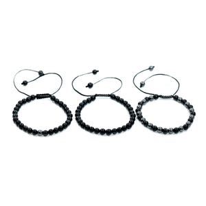 Op de afbeelding: Drie zwarte kralenarmbanden met verstelbare trekkoorden worden getoond tegen een witte achtergrond. Elke armband heeft kleine, ronde kralen en een schuifknoopsluiting voor een aanpasbare pasvorm. De armbanden zijn een eenvoudig, elegant accessoire.