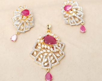 Può includere: Un set di collana con ciondolo e orecchini in oro con una pietra preziosa rossa e pietre di zircone cubico trasparenti. Il ciondolo e gli orecchini presentano un design floreale.