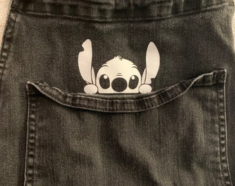 May include: Black denim overalls with a white Stitch character peeking out of the pocket.
