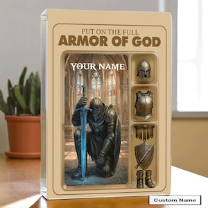 Puede incluir: Una caja beige con un caballero arrodillado con una espada azul brillante, sobre un fondo de iglesia. Se muestra el texto "PUT ON THE FULL ARMOR OF GOD" y "YOUR NAME". Se muestran piezas de armadura adicionales.
