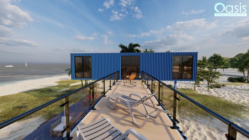 Render of a pre-engineered shipping container home (C1), showcasing a sustainable, modern, and minimalist design, perfect for a tiny modular metal home. A blue container home with a wooden deck and black railing. The deck has two white lounge chairs and a brown chair. The home is on a sandy beach with green grass and palm trees. The ocean is in the background with a sailboat in the distance. The text 'Oasis Engineering' is visible in the upper right corner of the image.