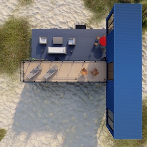 Render of a pre-engineered shipping container home (C1), showcasing a sustainable, modern, and minimalist design, perfect for a tiny modular metal home. A blue container home with a wooden deck and a railing. The deck has a lounge chair, a table with a red umbrella, and two chairs. The container home is on a sandy beach with green grass and trees.