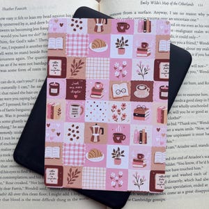 May include: A rectangular sticker featuring a grid pattern of pink, cream, and brown squares. The design includes illustrations of books, coffee mugs, moka pots, croissants, potted plants, and flowers. Some squares contain text such as "Just one more chapter" and "Books coffee happy".