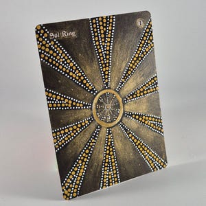 May include: A rectangular game card titled Sol Ring with the number 1 in the top right corner. The card features a dark brown background with a central gold circle and radiating lines composed of small white and yellow dots in a sunburst pattern.