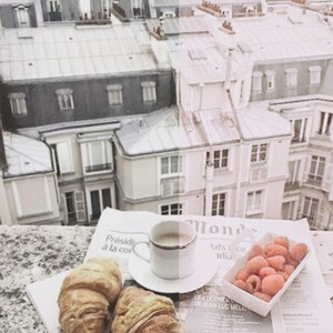 May include: A Parisian rooftop view with a cup of coffee, two croissants, and a container of raspberries on a newspaper. The newspaper has the text "Pr&eacute;sid &agrave; la cor" and "Mond ats 1 ce adia" printed on it.