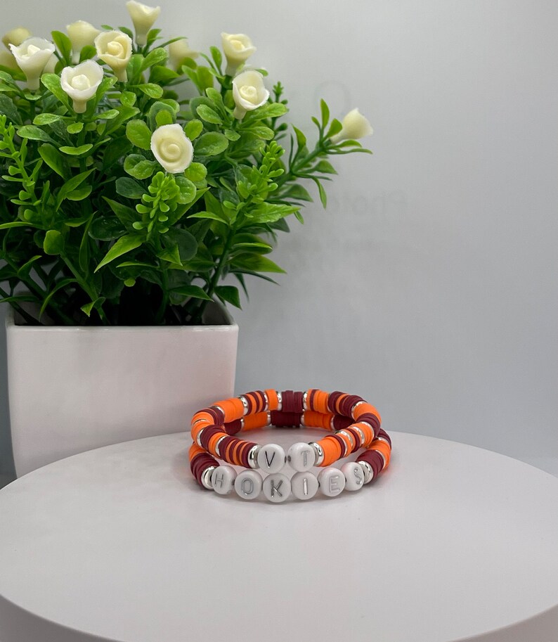 May include: Two bracelets with orange and maroon beads, spelling out "VT" and "HOKIES" in white letters.