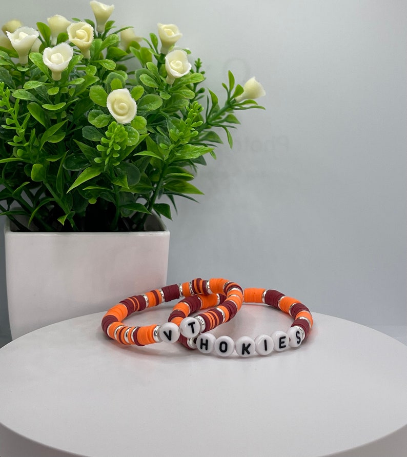 May include: Two bracelets made of orange and maroon beads with the word "HOKIES" spelled out in white letters.