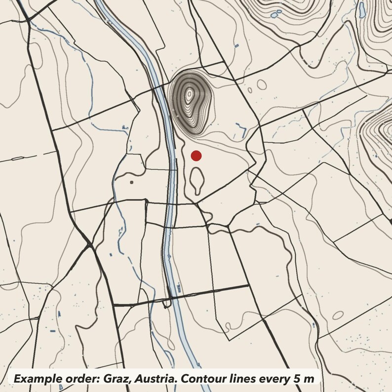 May include: A topographic map print featuring black contour lines on a light beige background. A prominent river flows vertically through the centre, with a shaded hill and a single red dot marking a specific location. Text reads: Example order: Graz, Austria. Contour lines every 5 m.