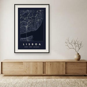 May include: A framed wall art print featuring a dark blue map of Lisbon with white street lines and topographic contours. The text LISBOA is printed in white capital letters below the map, followed by geographic coordinates in small text.