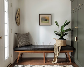 May include: A black leather bench with wooden legs sits in a hallway with a green cabinet, a houseplant in a woven basket, and a framed print on the wall.