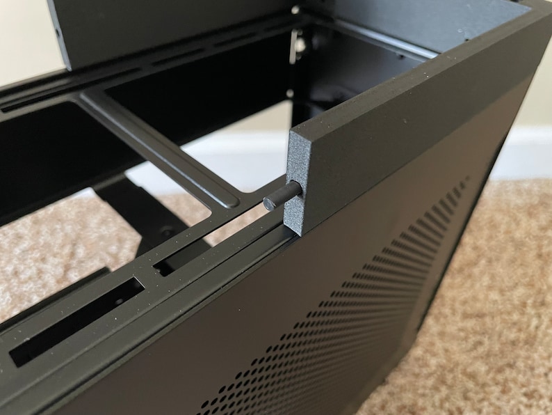 May include: A black computer case with a removable top panel. The panel is held in place by a small black pin.