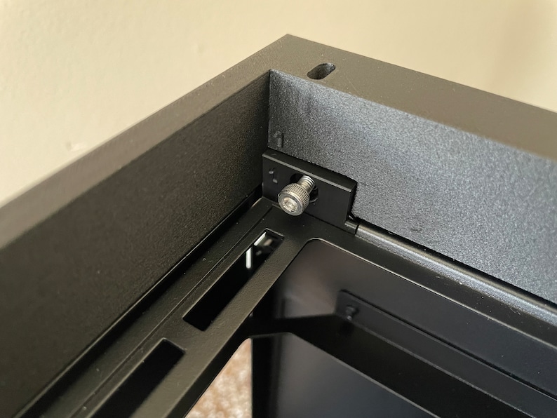 May include: Close-up of a black computer case with a metal screw securing a panel. The screw is silver and has a hexagonal head.