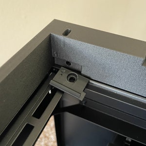 May include: Close-up of a black computer case with a black plastic screw cover labeled "1" on the top edge.