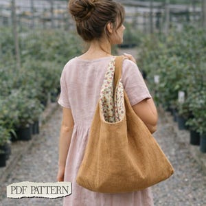 May include: A hobo-style shoulder bag made of solid tan fabric with a floral patterned interior lining. The bag features a wide, integrated shoulder strap and a slouchy, unstructured shape. The text PDF PATTERN is visible in the bottom corner.