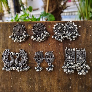 May include: Six pairs of silver tone earrings with various designs, including peacocks, elephants, and geometric shapes. Each pair features a dangling design with small beads.