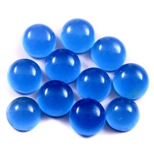 Może przedstawiać: Kolekcja jedenastu przezroczystych, okrągłych, niebieskich szklanych kulek. Kulki mają żywy odcień niebieskiego i wydają się gładkie i wypolerowane. Ułożone są w grupie na białym tle.
