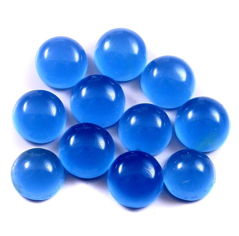 Może przedstawiać: Kolekcja jedenastu przezroczystych, okrągłych, niebieskich szklanych kulek. Kulki mają żywy odcień niebieskiego i wydają się gładkie i wypolerowane. Ułożone są w grupie na białym tle.