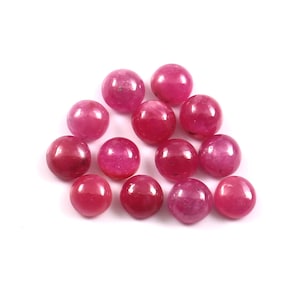 May include: A cluster of spherical, polished gemstones in shades of pink and red. The stones are displayed on a white background, highlighting their smooth, round form and natural colour variations. These gemstones are suitable for jewellery making.