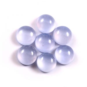 Puede incluir: Siete gemas redondas, de color azul p&aacute;lido, dispuestas en un patr&oacute;n circular sobre un fondo blanco. Las piedras tienen una superficie lisa y pulida y una calidad transl&uacute;cida, con un sutil degradado de color.