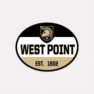 May include: An oval-shaped sticker featuring the words "WEST POINT" in bold, black letters. Below, in smaller text, it reads "EST. 1802." The top portion is black, the middle white, and the bottom a tan color. A gold and black crest is at the top.