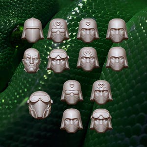 Puede incluir: Un conjunto de trece cabezas en miniatura de resina para figuras de juego. El set incluye varios diseños con cascos que presentan visores, gafas y emblemas de calaveras, junto a una cabeza descubierta con expresión facial seria y rasgos definidos.