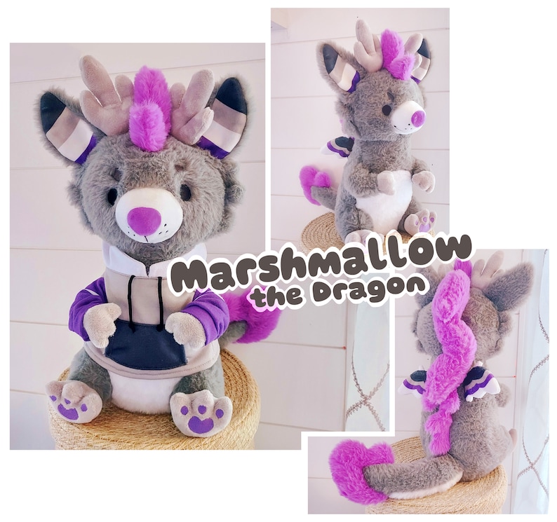May include: A gray plush dragon with purple accents and a pink mohawk. The dragon is wearing a gray hoodie with a black zipper and purple sleeves. The dragon is sitting on a woven basket. The text "Marshmallow the Dragon" is written in a purple font on a white background.