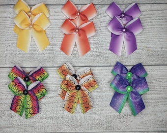 May include: Six pairs of colorful hair bows. The bows are made of ribbon and have a variety of patterns, including ombre, swirls, and glitter. The bows are perfect for adding a touch of whimsy to any hairstyle.