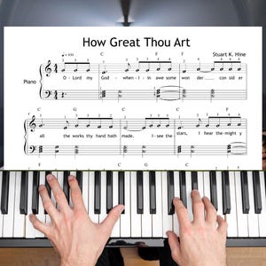 Può includere: È visibile una tastiera di pianoforte con uno spartito intitolato "How Great Thou Art". Lo spartito è sopra i tasti del pianoforte. Il testo "How Great Thou Art" e il nome del compositore sono visibili. Le mani di una persona stanno suonando il pianoforte.
